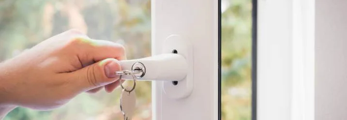 Hand schließt Fenster mit Schlüssel ab